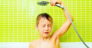boy holding removable shower head over head