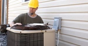 technician in yellow hard hat and outdoor hvac unit